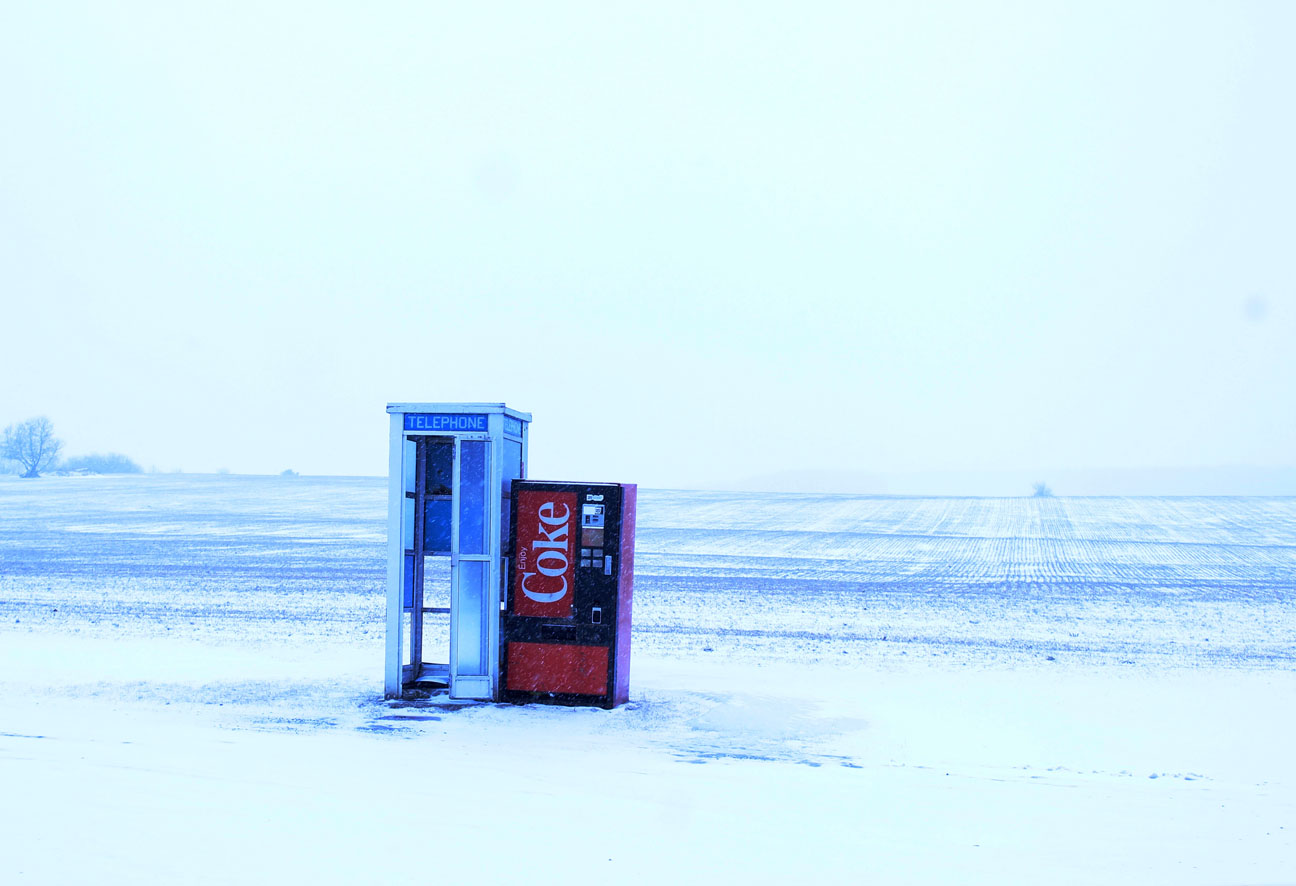 Image of a telephone booth and Coke machine in the middle of a field